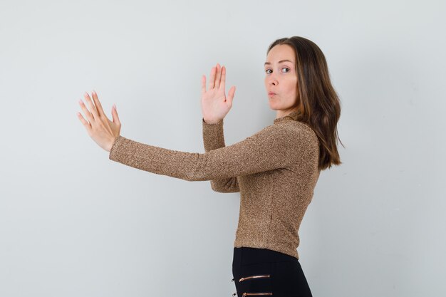 Junge Frau in der goldenen Bluse, die Karate-Kotelett zeigt und konzentriert schaut.