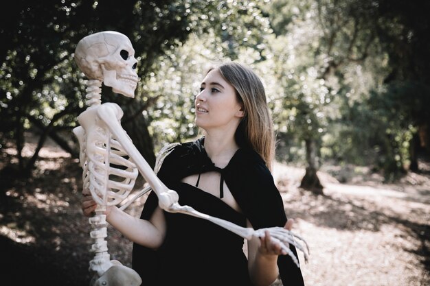 Junge Frau in der Hexe kleidet das Halten des Skeletts
