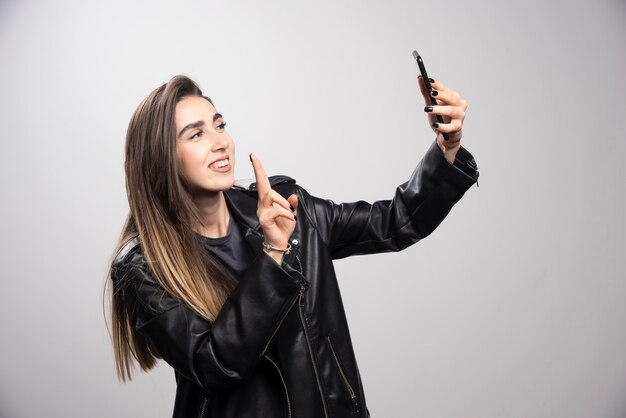 Junge Frau in der Lederjacke, die selfie mit ihrem Handy nimmt