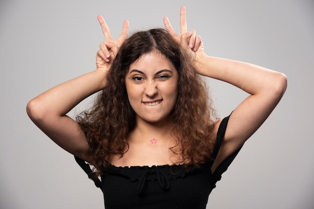 Junge Frau in der schwarzen Bluse mit dem aufwirbelnden lockigen Haar. Hochwertiges Foto