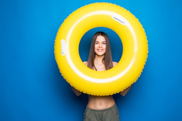 Junge Frau in der Sommerkleidung mit aufblasbarem Ring lokalisiert über blauer Wand.