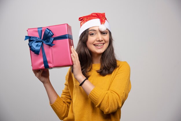 Junge Frau in der Weihnachtsmütze, die eine Geschenkbox hält.