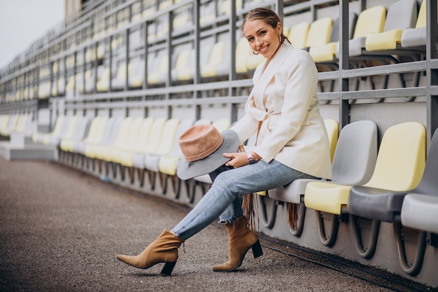 Junge Frau in der weißen Jacke, die Hut hält