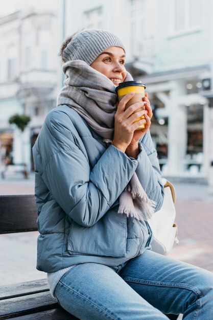 Junge Frau in der Winterkleidung, die eine Tasse Kaffee hält