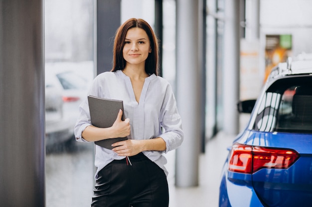 Junge Frau in einem Autosalon, der ein Auto wählt