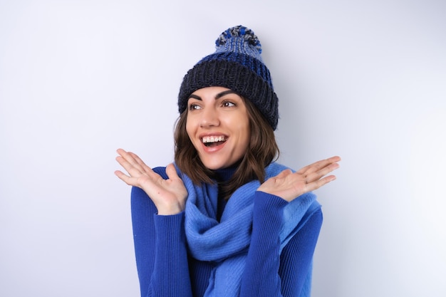 Junge Frau in einem blauen Rollkragenpullover und Schal auf weißem Hintergrund fröhlich in guter Laune