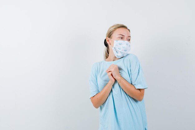 Junge Frau in einem blauen T-Shirt mit einer medizinischen Maske