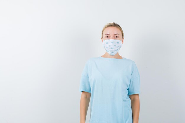 Junge Frau in einem blauen T-Shirt mit einer medizinischen Maske