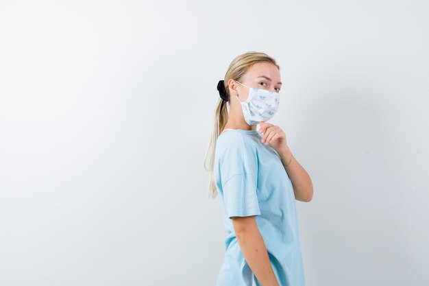 Junge Frau in einem blauen T-Shirt mit einer medizinischen Maske