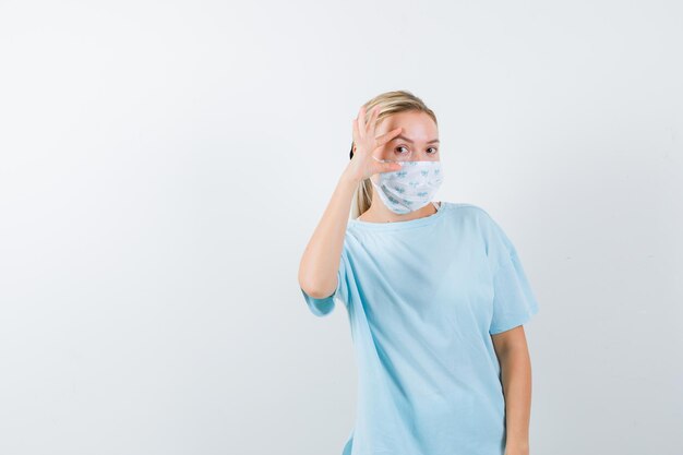 Junge Frau in einem blauen T-Shirt mit einer medizinischen Maske