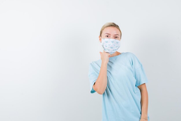 Junge Frau in einem blauen T-Shirt mit einer medizinischen Maske