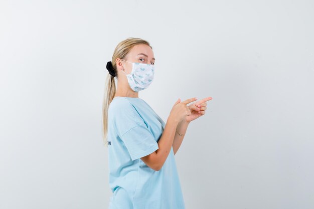 Junge Frau in einem blauen T-Shirt mit einer medizinischen Maske