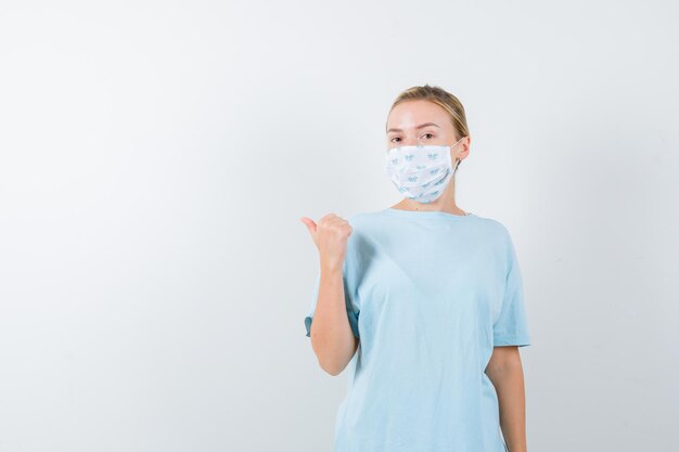 Junge Frau in einem blauen T-Shirt mit einer medizinischen Maske