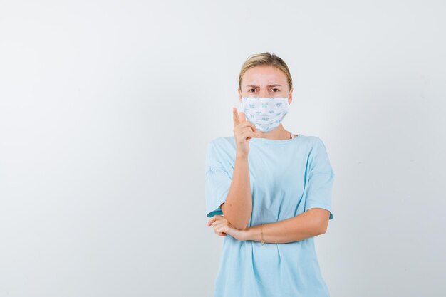 Junge Frau in einem blauen T-Shirt mit einer medizinischen Maske