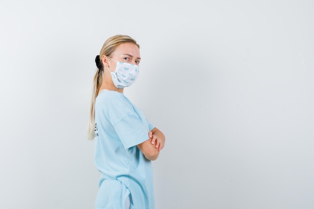 Junge Frau in einem blauen T-Shirt mit einer medizinischen Maske