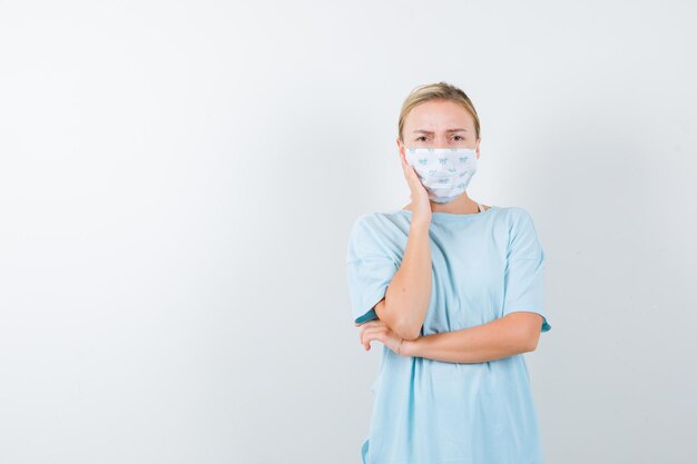 Junge Frau in einem blauen T-Shirt mit einer medizinischen Maske