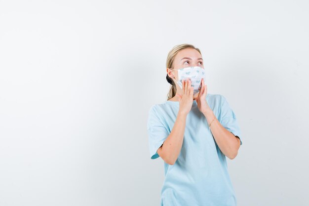 Junge Frau in einem blauen T-Shirt mit einer medizinischen Maske