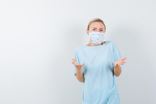 Junge Frau in einem blauen T-Shirt mit einer medizinischen Maske