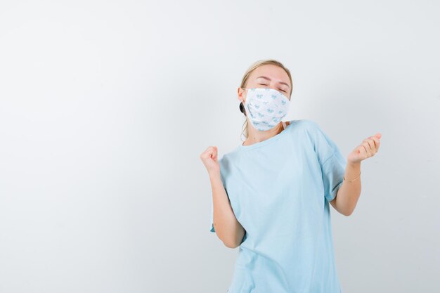 Junge Frau in einem blauen T-Shirt mit einer medizinischen Maske