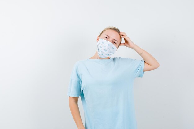 Junge Frau in einem blauen T-Shirt mit einer medizinischen Maske
