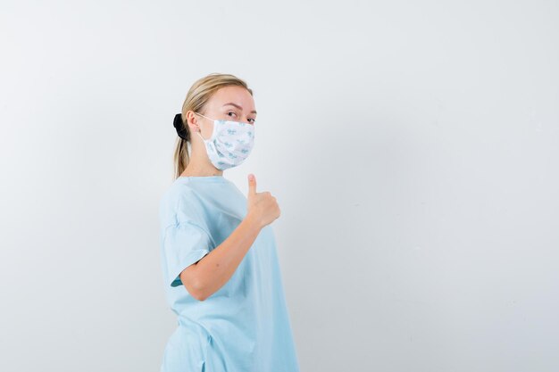 Junge Frau in einem blauen T-Shirt mit einer medizinischen Maske
