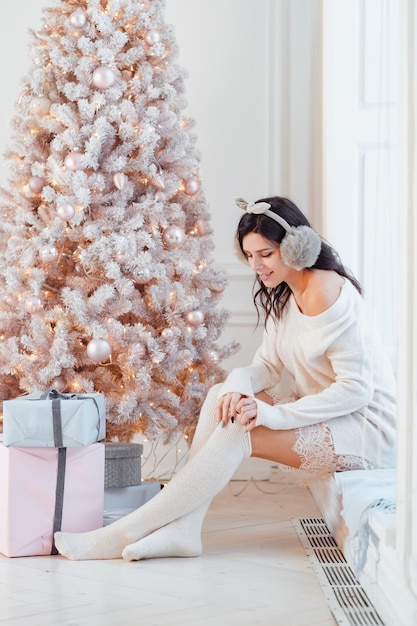 Junge Frau in einem eleganten Kleid nahe dem Weihnachtsbaum