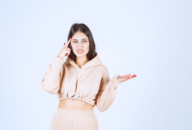 Junge Frau in einem rosa Kapuzenpulli, der etwas in ihrer offenen Hand präsentiert