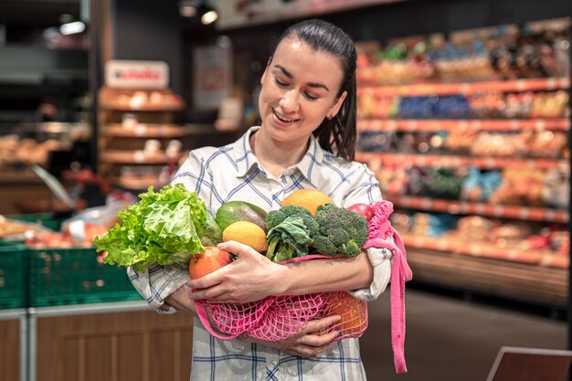 Junge Frau in einem Supermarkt mit Gemüse und Obst, die Lebensmittel kauft