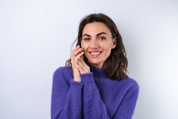Junge Frau in einem violetten, weichen, kuscheligen Pullover auf dem Hintergrund eines süßen Lächelns, das fröhlich in Hochstimmung ist, selbstbewusstes Lächelnx9