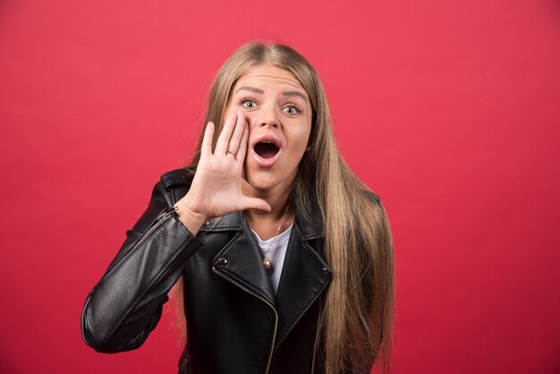 Junge Frau in Freizeitkleidung, die mit der Hand auf dem Mund laut schreit und schreit