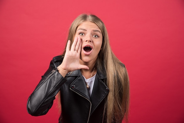 Junge Frau in Freizeitkleidung, die mit der Hand auf dem Mund laut schreit und schreit