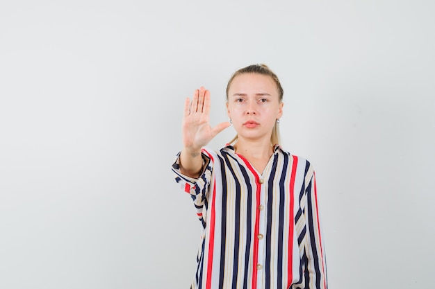 Kostenloses Foto junge frau in gestreifter bluse, die stoppgeste zeigt und wütend aussieht