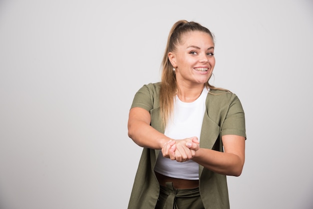 Junge Frau in grüner Jacke, die ihre eigenen Hände hält.