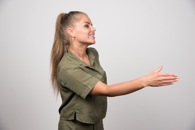 Junge Frau in grüner Jacke, die ihre Hand zum Schütteln anbietet.