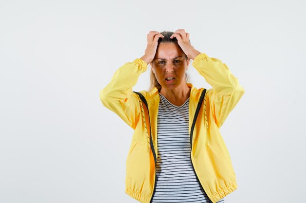 Kostenloses Foto junge frau in jacke, t-shirt, das hände auf kopf hält und wehmütig schaut, vorderansicht.