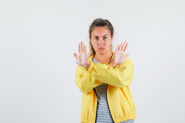 Kostenloses Foto junge frau in jacke, t-shirt zeigt stoppgeste und sieht ernst aus, vorderansicht.