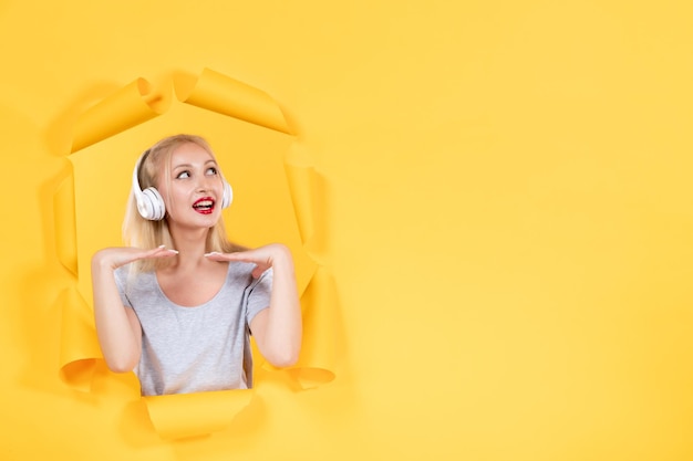 Junge Frau in Kopfhörern auf gelbem Hintergrundaudio klingt Ultraschallmusik