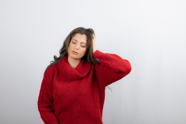 Junge Frau in roter warmer Strickjacke, die unter Kopfschmerzen leidet.
