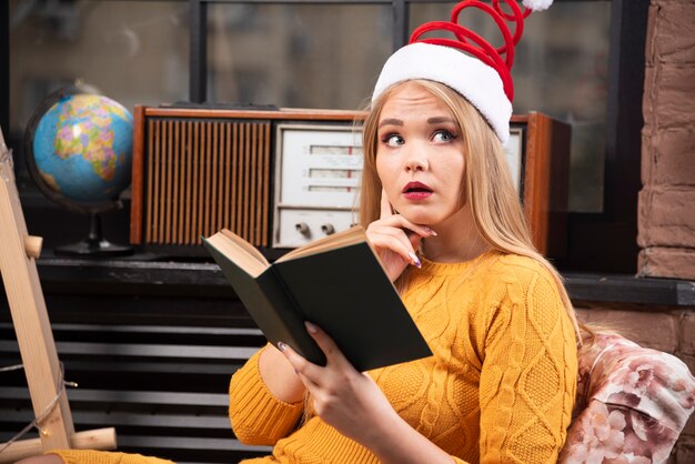 Junge Frau in Santa Hut ein Buch zu lesen.