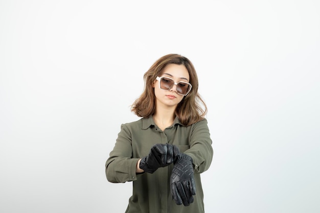 Junge Frau in schwarzen Handschuhen und Brille posiert und steht. Foto in hoher Qualität