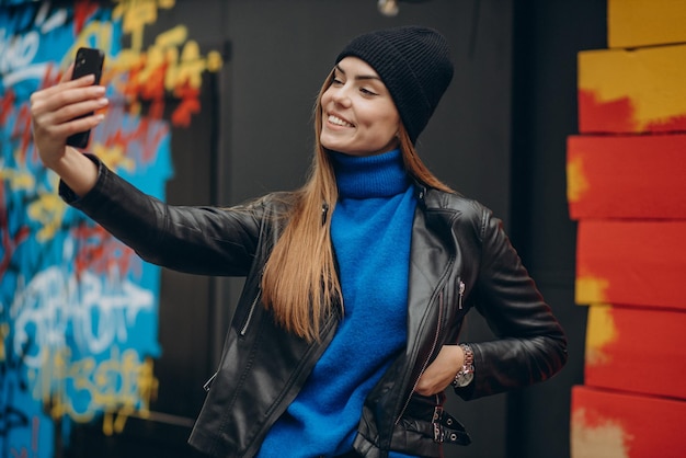 Junge Frau in schwarzer Jacke mit Telefon