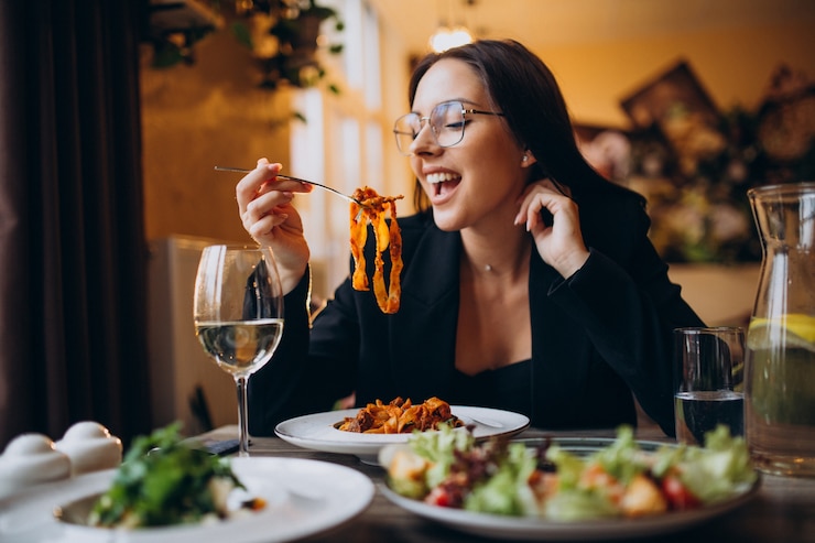 Kostenlose Foto junge frau isst pasta in einem café