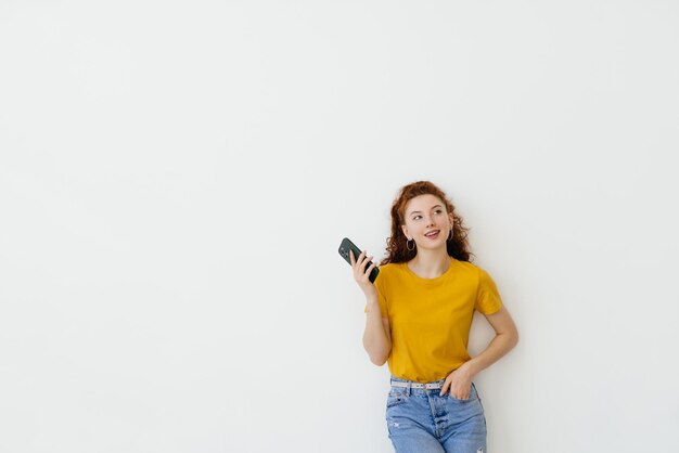 Junge Frau liest Nachricht auf dem Smartphone und lächelt in sozialen Netzwerken, während sie über weißem Hintergrund steht