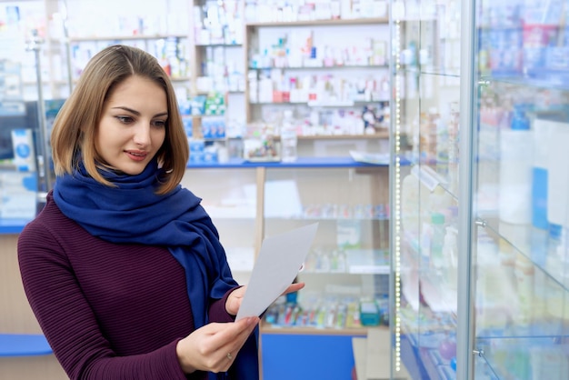 Junge Frau liest Rezept in der Apotheke