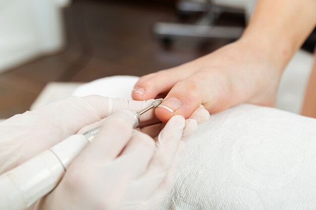 Junge Frau macht Pediküre im Salon. Schönheitskonzept.