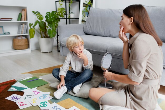 Junge Frau macht Sprachtherapie mit einem kleinen blonden Jungen