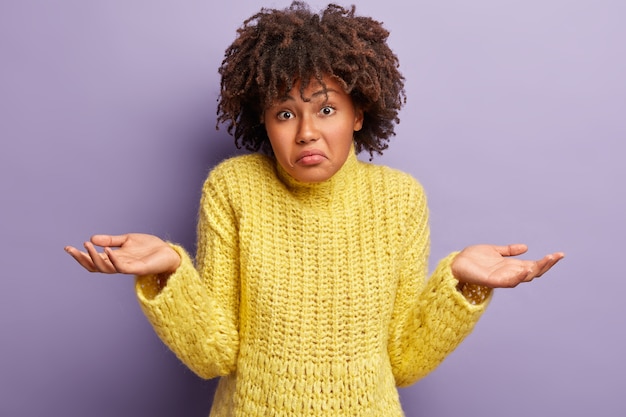 Junge Frau mit Afro-Haarschnitt, der gelben Pullover trägt