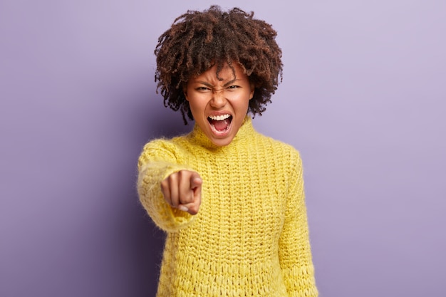 Junge Frau mit Afro-Haarschnitt, der gelben Pullover trägt