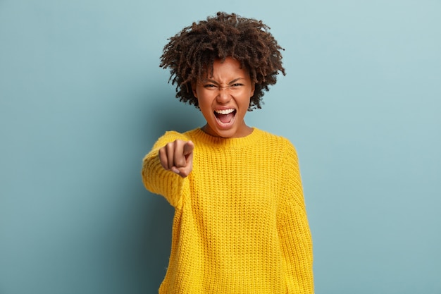 Junge Frau mit Afro-Haarschnitt, der gelben Pullover trägt