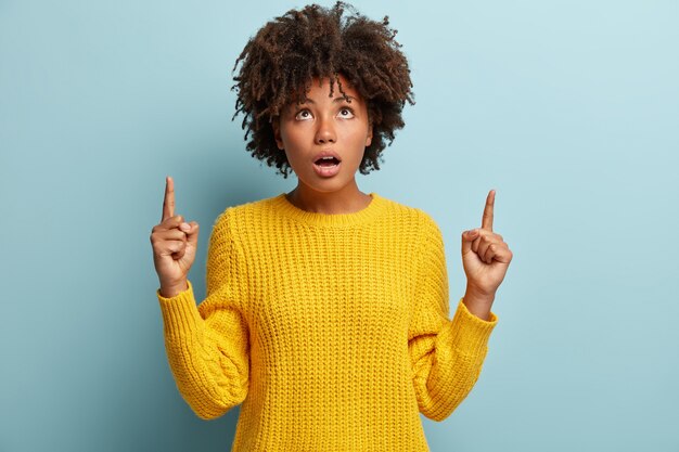 Junge Frau mit Afro-Haarschnitt, der gelben Pullover trägt